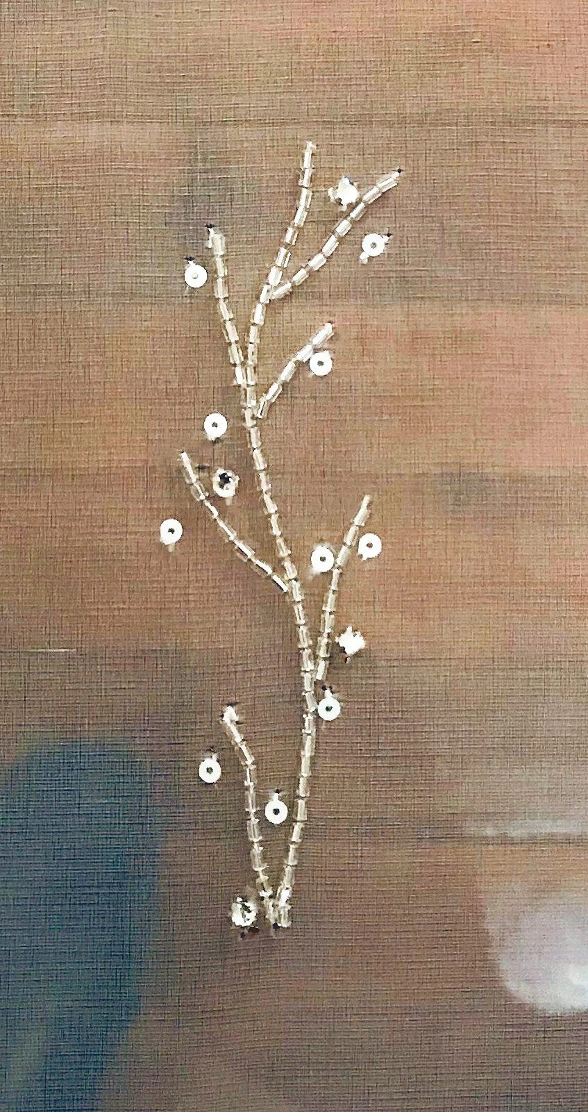 A beaded branch with small sequin flowers on brown organza.