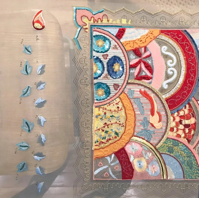 The sampler on the frame, with a column of pale blue leaves along the left edge.