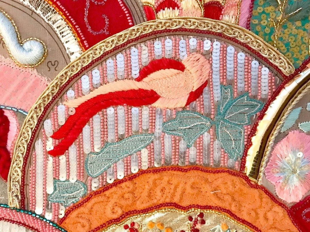 Detail: a bird in red and pink thread on a ground of white bugle beads.