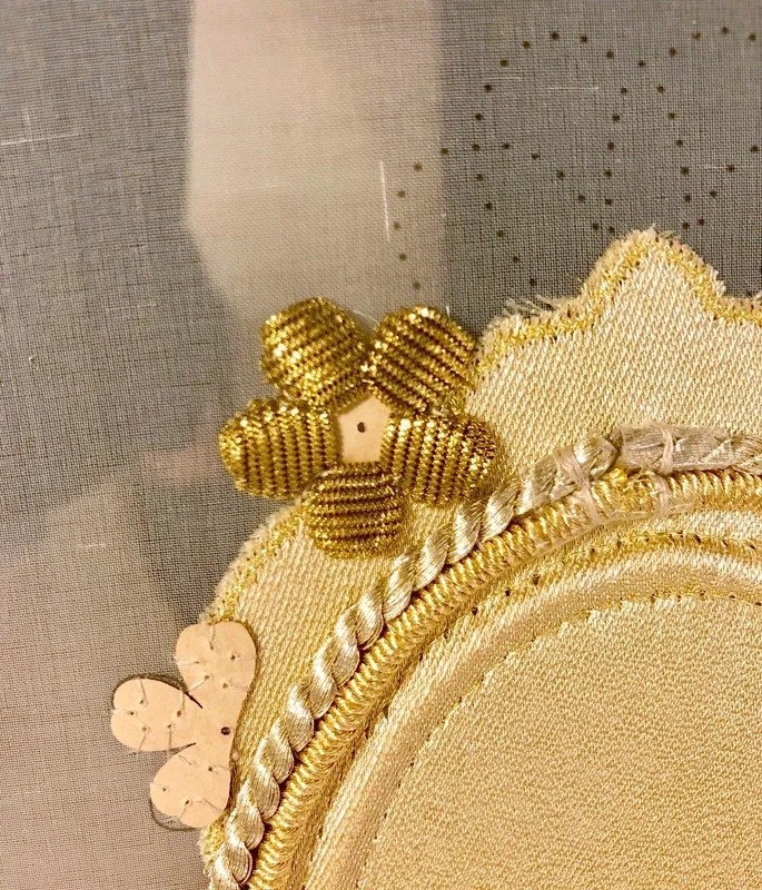 Detail of a goldwork flower in coiled purl at the edge of the oval.