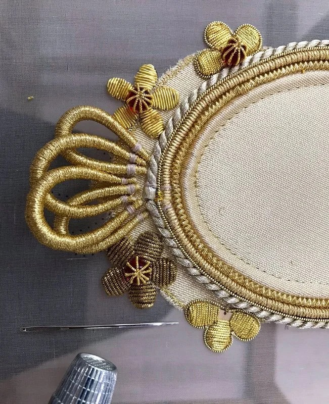 Detail of the oval frame: looped gold cord and cannetille flowers.