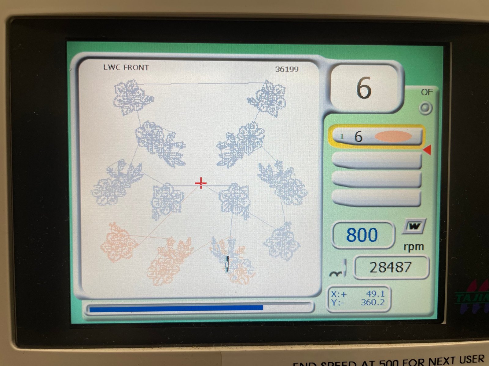 The embroidery machine's control panel showing the design file as a scatter of stitched motifs, with the stitch count and speed.