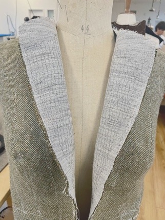 The roll line taped, lapels rolled and pressed, on the stand.