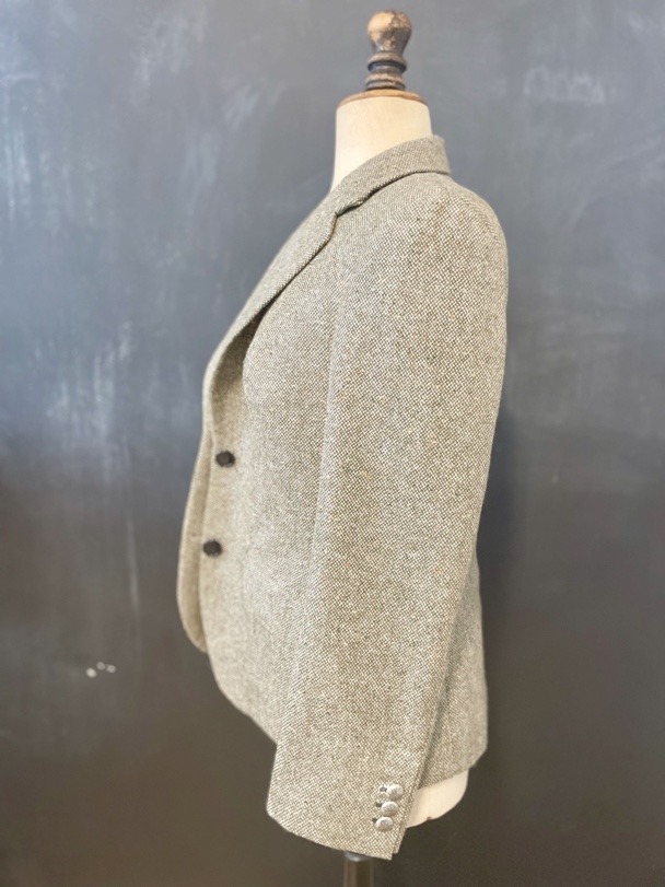 The finished tweed jacket on a dress form, seen from the side.